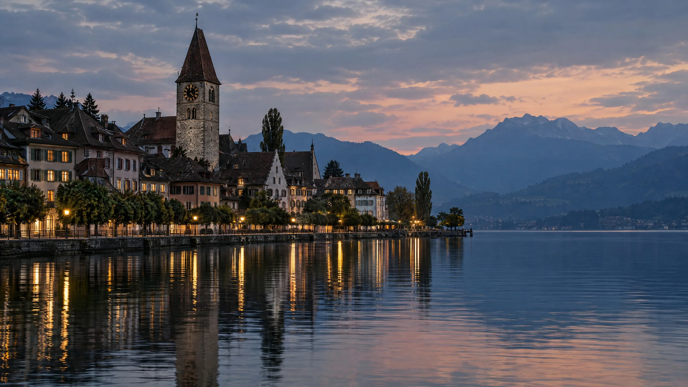 An old town on the shore of a Swiss lake at dusk, its clock tower and houses reflected in the water