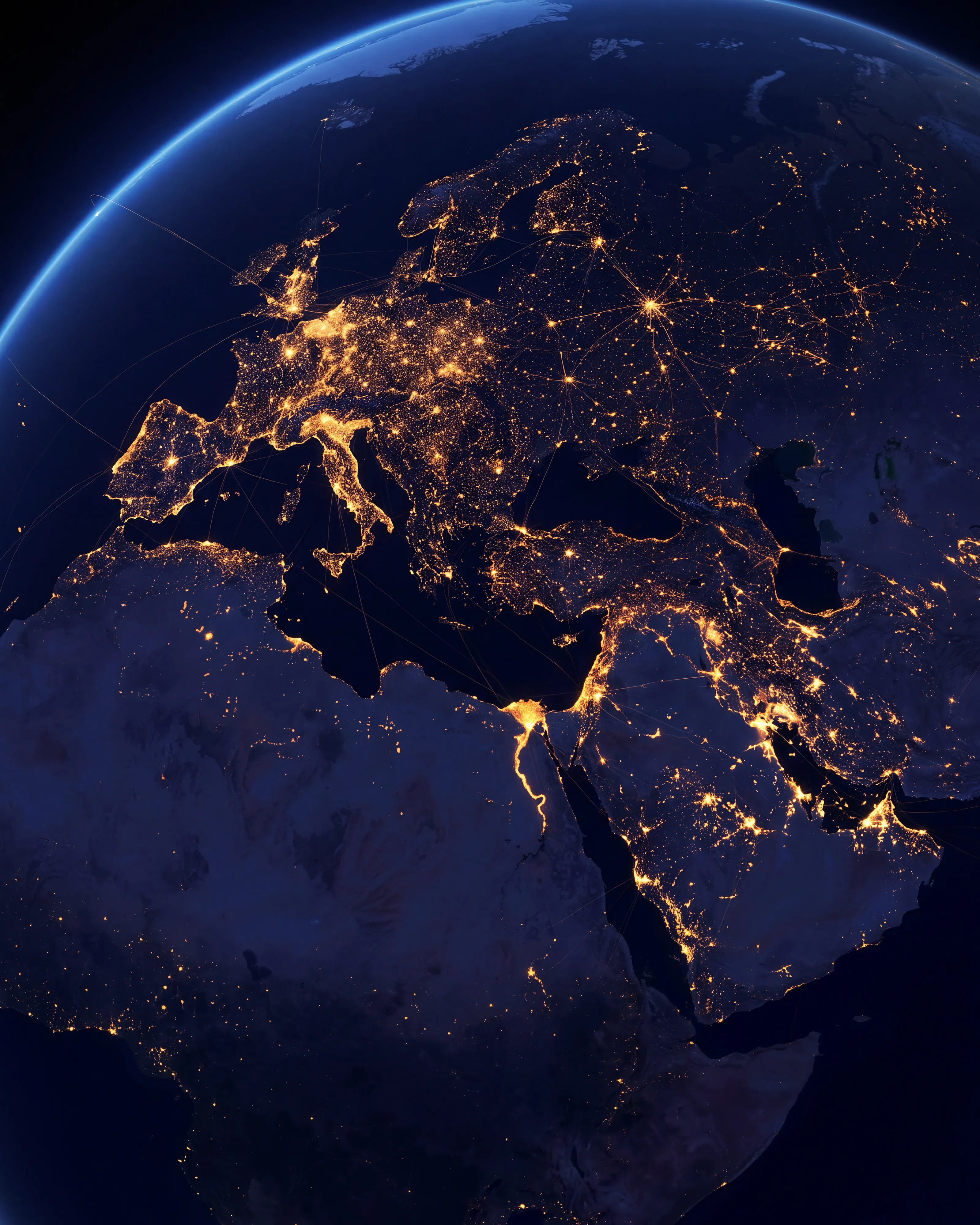 The earth at night, seen from orbit, city lights tracing the routes of a global network